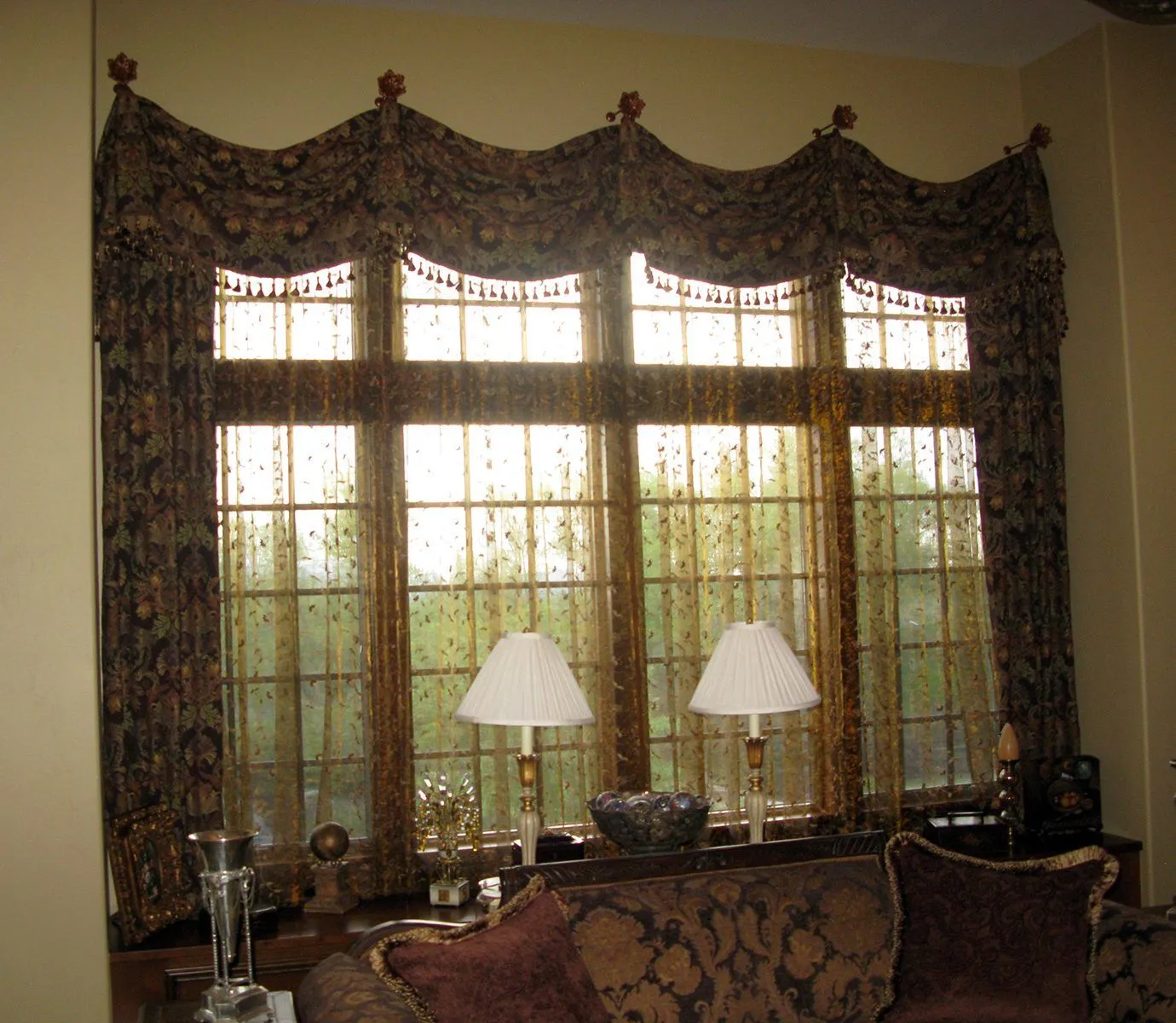 Ornate scarf valance and sheer drapery over a large arched window