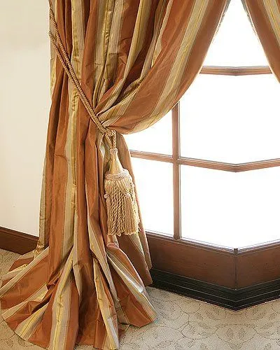 Striped silk drapery panel with a tasseled tieback at a window